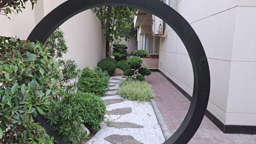 "Serene residential Zen garden with bonsai trees and gravel path – Executed by LandscapeCompany.pk"